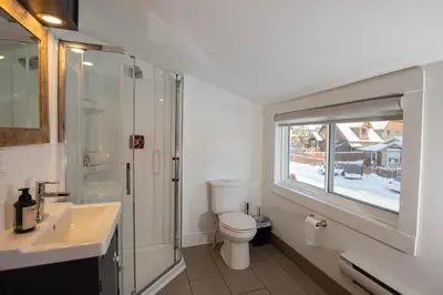 a bathroom with a toilet and a sink and a window at Mountain View Retreat in the heart of Banff - Massive House Sleeps 23 in Banff