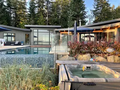 a house with a hot tub in the yard at Cokely Cove Guesthouse - Oceanside Villa in Denman Island