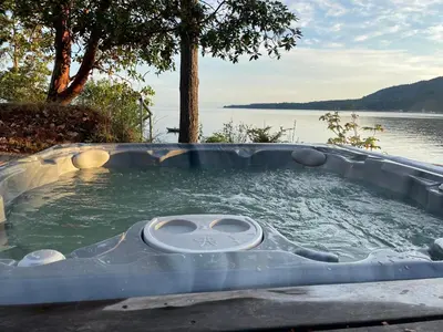 a jacuzzi tub with a view of a lake at Cokely Cove Guesthouse - Oceanside Villa in Denman Island