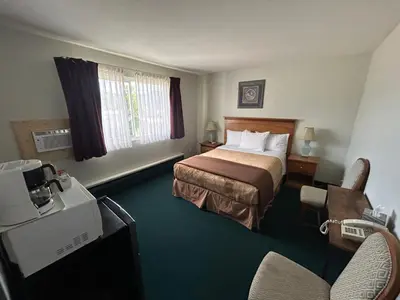 a hotel room with a bedroom with a bed and a television at Marina Hotel in Port Alberni