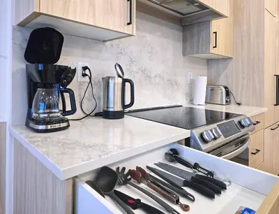 a kitchen with a counter with utensils on it at Family Modern 1BR and Den Condo - Apartment with City View, Downtown, Balcony, Free Parking & In-Suite Laundry! in Calgary