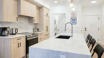 a kitchen with a sink and a counter top at Family Modern 1BR and Den Condo - Apartment with City View, Downtown, Balcony, Free Parking & In-Suite Laundry! in Calgary