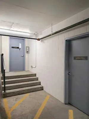 a hallway with stairs and a blue door at Family Modern 1BR and Den Condo - Apartment with City View, Downtown, Balcony, Free Parking & In-Suite Laundry! in Calgary