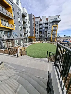 a grassy area in an apartment complex with buildings at Family Modern 1BR and Den Condo - Apartment with City View, Downtown, Balcony, Free Parking & In-Suite Laundry! in Calgary