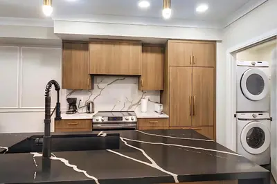a kitchen with a sink and a washer and dryer at Family Stylish 1BR and Den Condo -Apartment with City View, Downtown, Balcony, Free Parking, In-Suite Laundry! in Calgary