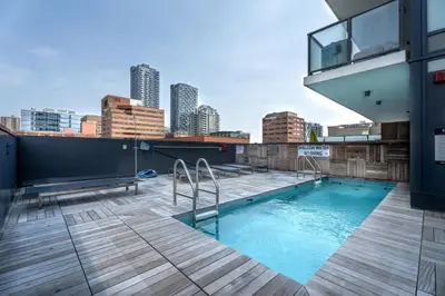 a swimming pool on the roof of a building with a city at Vibrant PopArt downtown suite, comfy and stylish! in Calgary