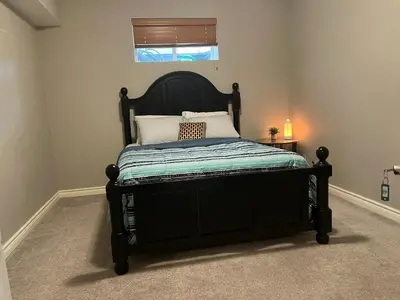 a black bed in a room with a window at Rooms for Hosting in Calgary