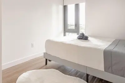 a bed in a white room with a large window at Scenic 2BR RiverView Suite in Downtown in Calgary
