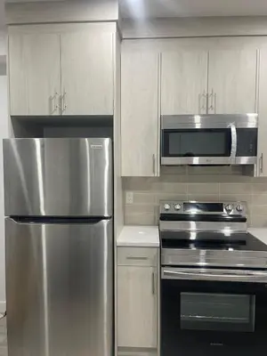 a kitchen with a stainless steel refrigerator and a microwave at Cozy Inn new basemt wt sep entrance contains 1 bdrm and den for up to 4 guests in Airdrie