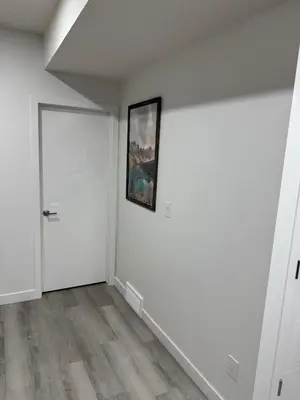 an empty room with a door and a painting on the wall at Cozy Inn new basemt wt sep entrance contains 1 bdrm and den for up to 4 guests in Airdrie