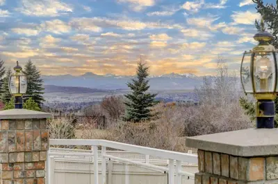 a porch with a white fence and mountains in the background at Spacious mountain view guesthouse in Calgary