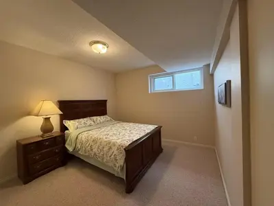 a bedroom with a bed and a lamp and a window at Spacious mountain view guesthouse in Calgary