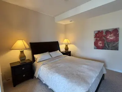 a bedroom with a bed and two lamps on tables at Spacious mountain view guesthouse in Calgary