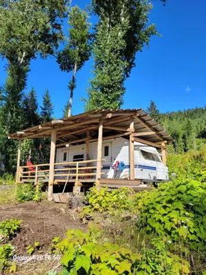 a rv with a wooden roof in a field at Rara's secret nest in Aiyansh