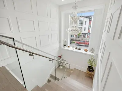 a white hallway with a staircase and a chandelier at Spacious 4BR Langley Home in Langley