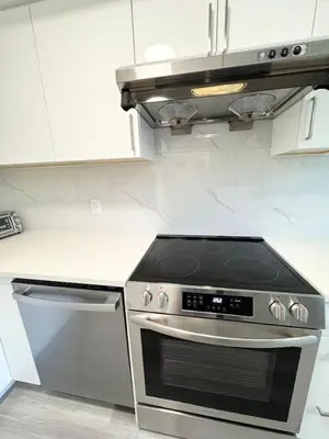 a stove top oven in a kitchen with white cabinets at Perfect Vancouver Travel Hub for Couples or Family in Vancouver