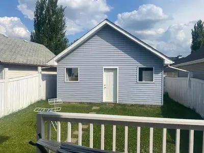a blue house with a white fence and a yard at Basement Appartment in Edmonton