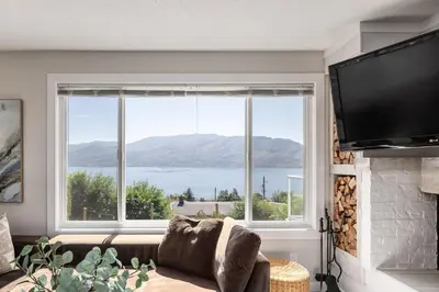 a living room with a large window and a couch at Magical Lake View in Peachland