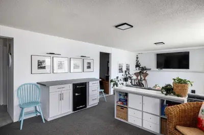 a kitchen with white cabinets and a blue chair at Magical Lake View in Peachland