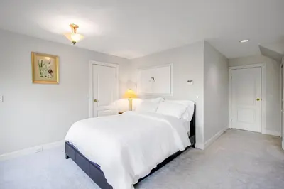 a white bedroom with a large bed with white sheets at Garden Suite near Jericho Beach in Vancouver