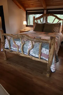 a wooden bed in a room with a window at Taylor Lake Resort BC in Lone Butte