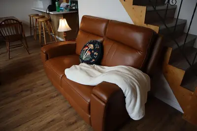 a brown leather couch with a blanket on it at Taylor Lake Resort BC in Lone Butte