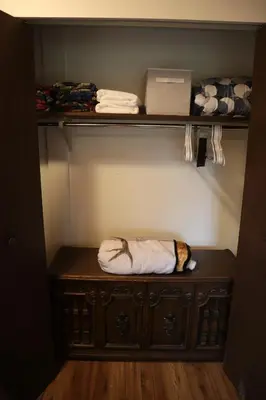 a closet with a wooden cabinet with towels at Taylor Lake Resort BC in Lone Butte