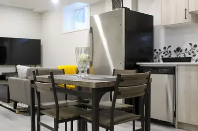 a kitchen with a table with chairs and a refrigerator at Cozy 2-Bedroom Walkout Basement Suite in Calgary