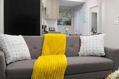 a couch with two pillows and a yellow blanket at Cozy 2-Bedroom Walkout Basement Suite in Calgary