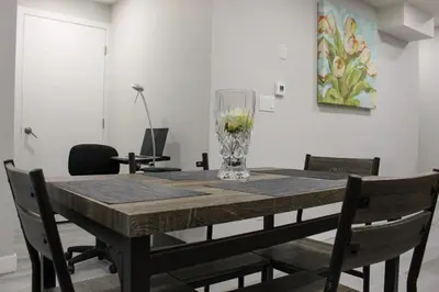 a dining room table with a glass vase on it at Cozy 2-Bedroom Walkout Basement Suite in Calgary