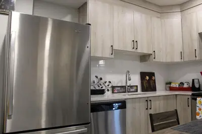 a stainless steel refrigerator in a kitchen with wooden cabinets at Cozy 2-Bedroom Walkout Basement Suite in Calgary