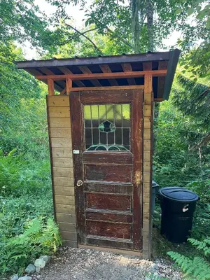 an outhouse with an open door in the grass at Tree Top Sanctuary Cowichan Valley in Duncan