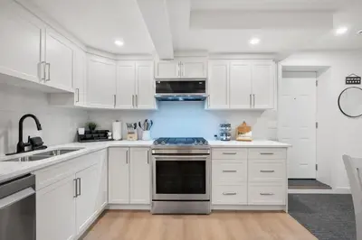 a kitchen with white cabinets and a stove top oven at Meadowstone Suite 3BD 3 TVs Near Spruce Meadows in Calgary