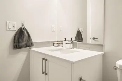 a white bathroom with a sink and a mirror at Large Single Family 3 Bedroom House with Air Conditioner, Garage and Lake View in Calgary