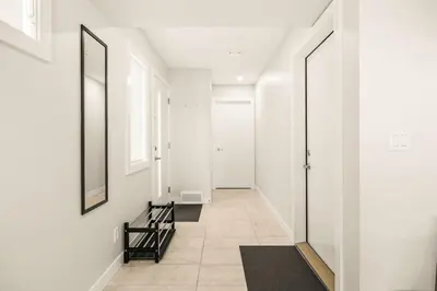 a hallway with white walls and a staircase with a mirror at Large Single Family 3 Bedroom House with Air Conditioner, Garage and Lake View in Calgary