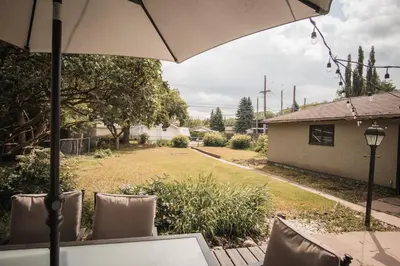 a table with an umbrella in a yard at Play & Stay - Downtown Sleeps 10 in Edmonton