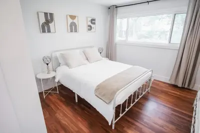 a white bedroom with a bed and a window at Play & Stay - Downtown Sleeps 10 in Edmonton