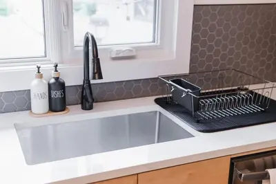 a kitchen sink with a dish rack next to it at Play & Stay - Downtown Sleeps 10 in Edmonton