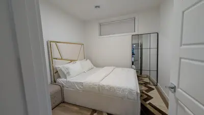 a small white bedroom with a bed and a mirror at Cozy 2-Bedroom Basement Suite Just Minutes from the Airport in Calgary