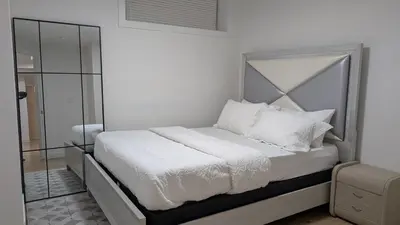 a white bedroom with a bed with white sheets and pillows at Cozy 2-Bedroom Basement Suite Just Minutes from the Airport in Calgary