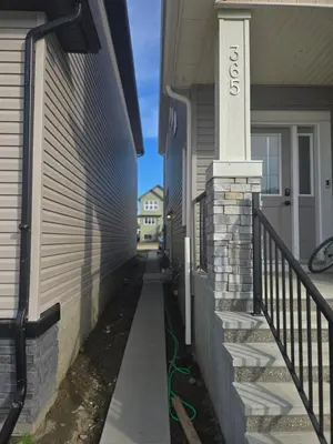 a house with a walkway next to a house at Cozy 2-Bedroom Basement Suite Just Minutes from the Airport in Calgary