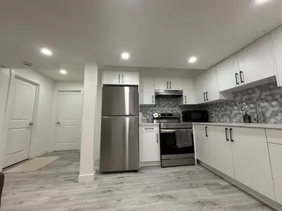 a kitchen with white cabinets and a stainless steel refrigerator at 2 bedroom Basement Suite in Calgary