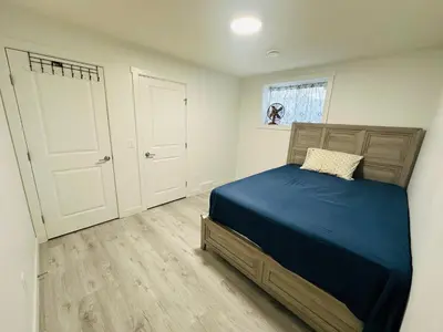 a bedroom with a bed with blue sheets and a window at 2 bedroom Basement Suite in Calgary