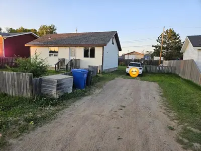a dirt road in a yard with a house and a car at Cozy Bungalow
