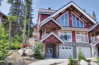 a red house with a garage and trees at Snow Reason A in Big White