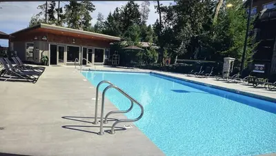 a large blue swimming pool with chairs in front of a building at Parksville Townhome 2 bedroom pool gym in Parksville