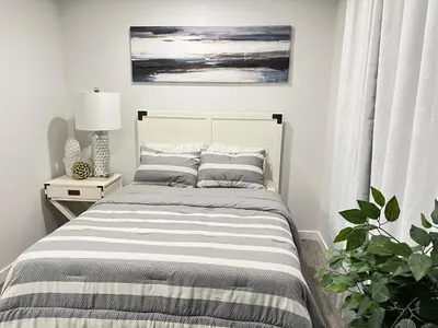 a bedroom with a bed with a striped blanket at 1-BR Suite with Private entrance near Restaurants, Shops, Local Amenities in Edmonton