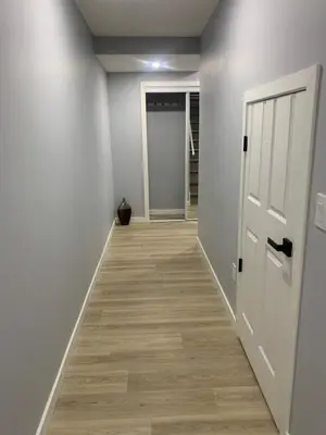 an empty hallway with a door and wooden floors at Modern 1BR Entire Suite Near Airport in Calgary