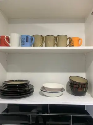 a shelf filled with plates and cups and bowls at Modern 1BR Entire Suite Near Airport in Calgary