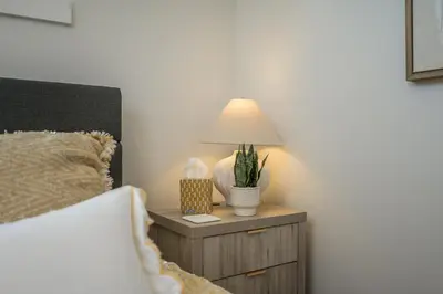 a bed with a nightstand with a lamp on it at Forest Haven on the Ridge in Prince George